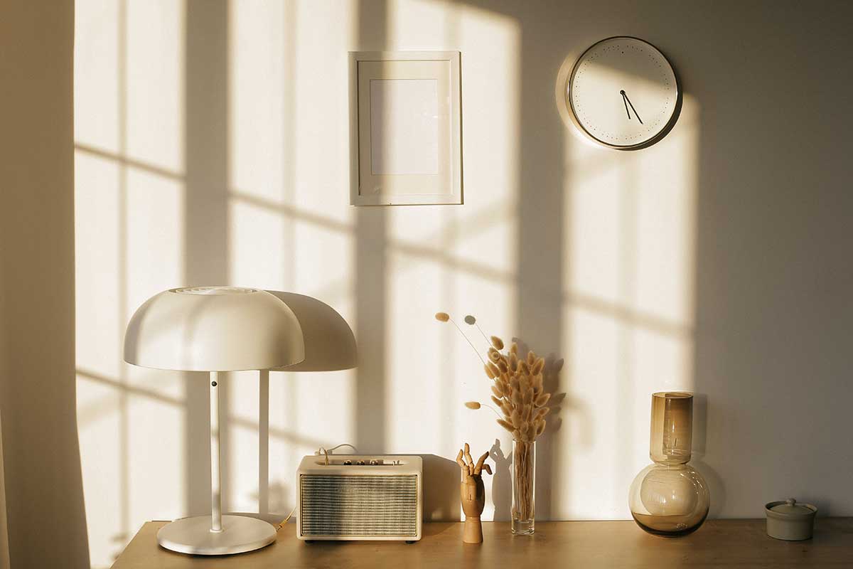 En trådløs lampe, lyst foto og klokke på veggen, og få pyntegjenstander på en benk, er alle gode innredningstips for en liten bolig.